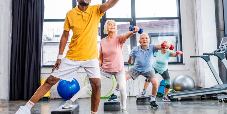 Elderly Group Exercising with Dumbbells in Fitness Class at Memory Care Facility